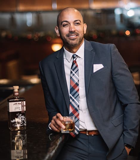 Resolute quality - A connoisseur enjoying Land Run Bourbon at a bar with the signature bottle showcasing Oklahoma's finest whiskey