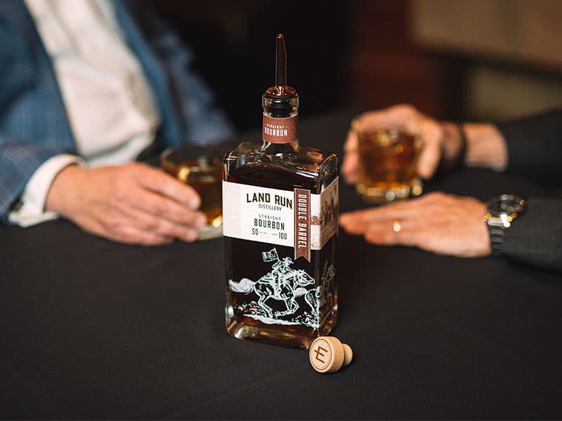 Premium whiskey being poured into a glass, showcasing the rich amber color of Land Run Distillery's bourbon